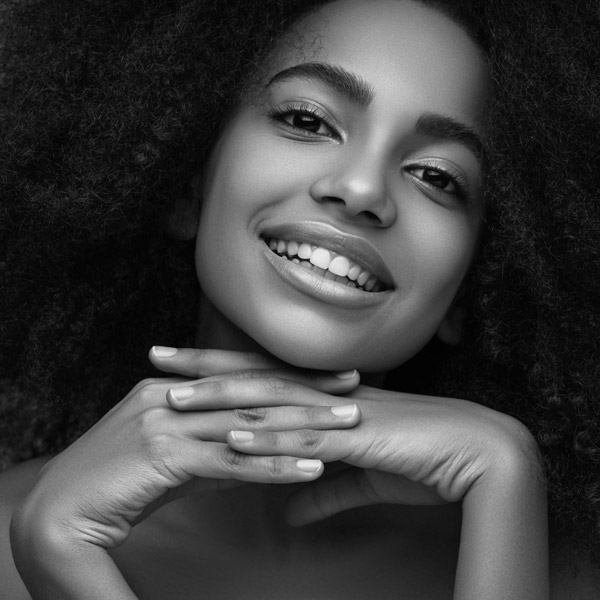 woman smiling with hands under her chin